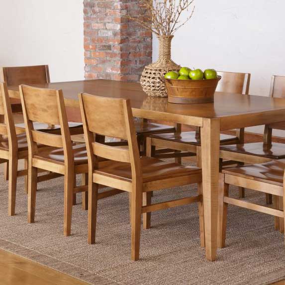 Maple modern dining chairs with panel backs and solid wood seats around a leg table by a brick wall