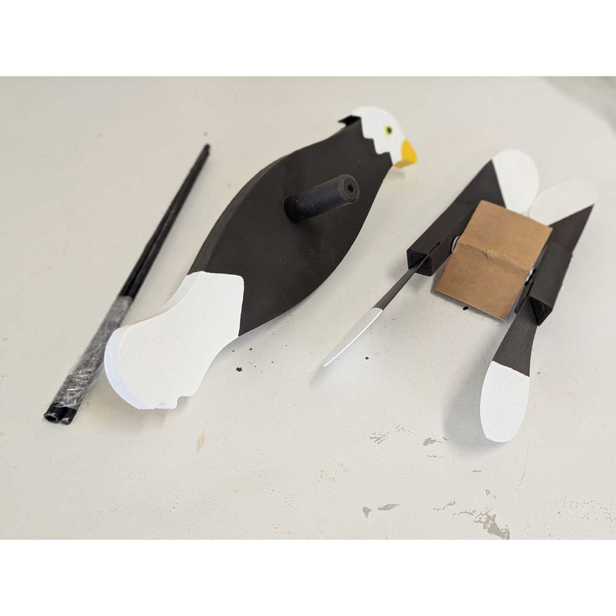 Disassembled eagle whirlybird kit on a workbench: body, replacement paddle wing set, rods and cardboard spacer