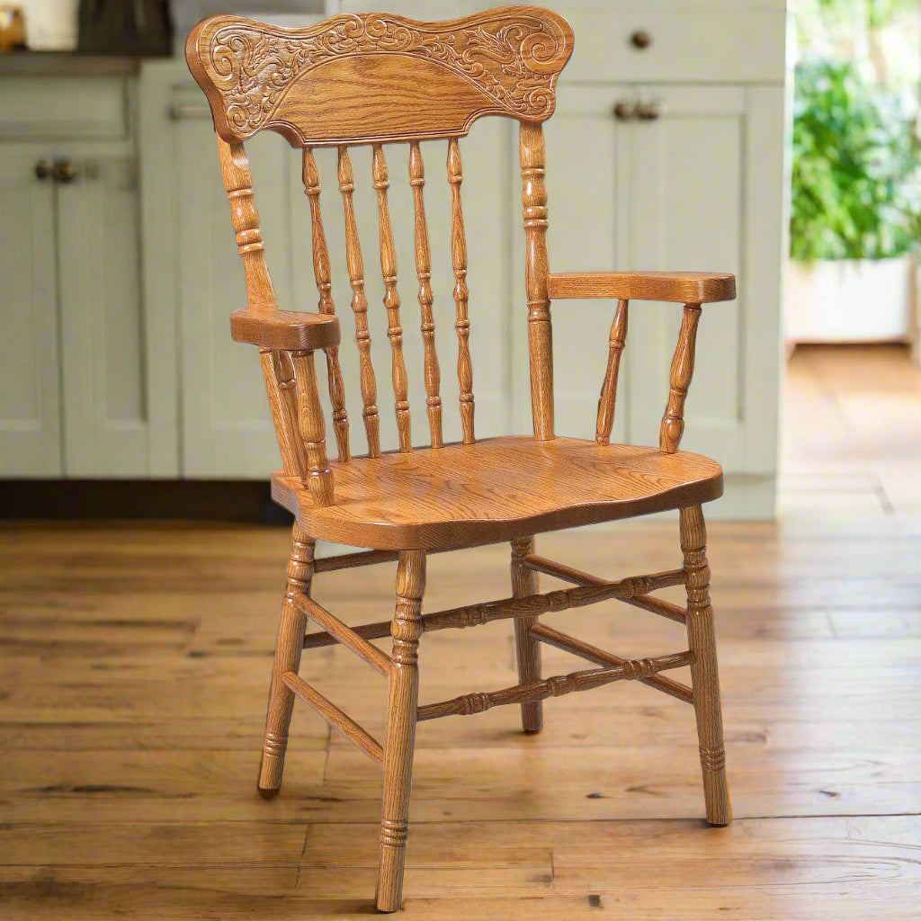 A classic Amish Windsor pressback dining chair with a carved backrest and spindle design, shown in an oak finish.