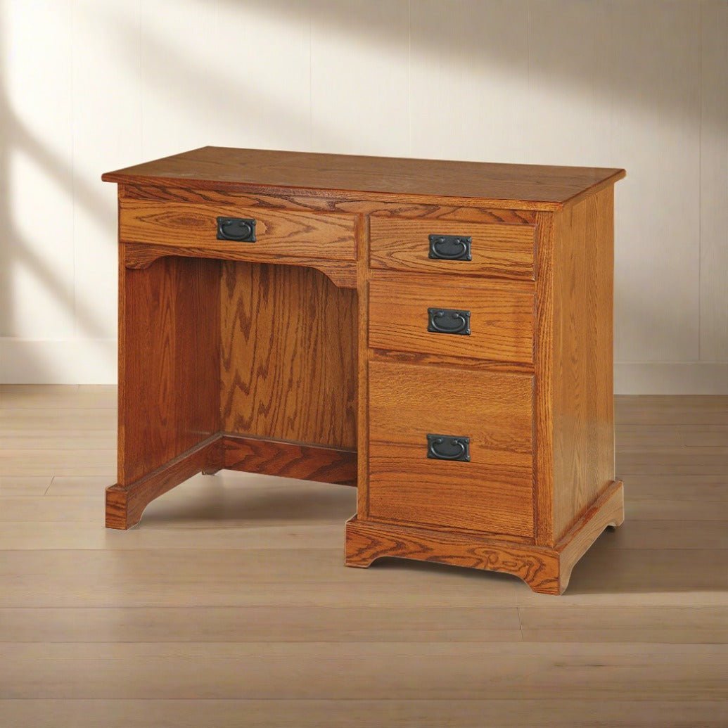 Oak writing desk with a single top drawer and three side drawers with black bail pulls in a sunlit room