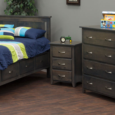 Gray stained 3-drawer nightstand between a storage bed and matching chest of drawers in a boy's bedroom with navy bedding