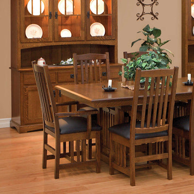 Mission oak dining chairs with vertical slat backs and black leather seats at a trestle table by a hutch