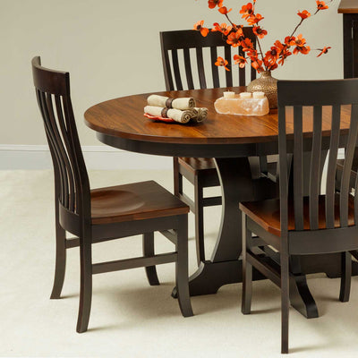 Two-tone dining chairs with black painted frames and cherry wood seats around a round pedestal table with fall florals