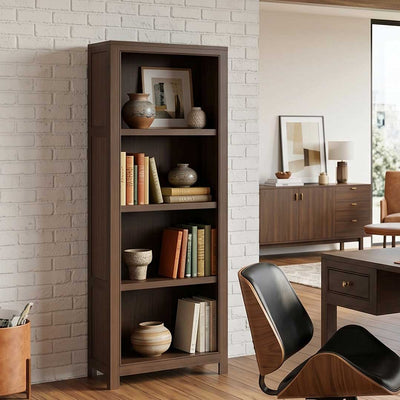 Tall narrow bookcase in dark walnut with four open shelves holding books and pottery against a white brick wall