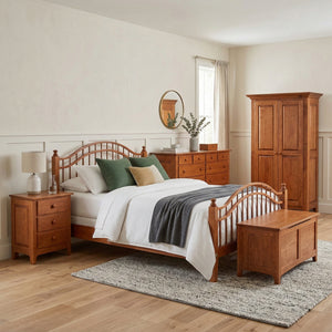 Cherry spindle bed with green pillows styled with nightstand, blanket chest, dresser and armoire