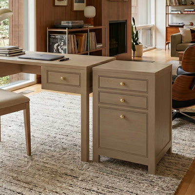 Home office with a light oak writing desk and a matching three drawer file cabinet with brass knobs on a wool rug