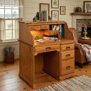 Oak roll top computer desk styled in a farmhouse room with lit interior cubbies, drawers and a stone fireplace behind