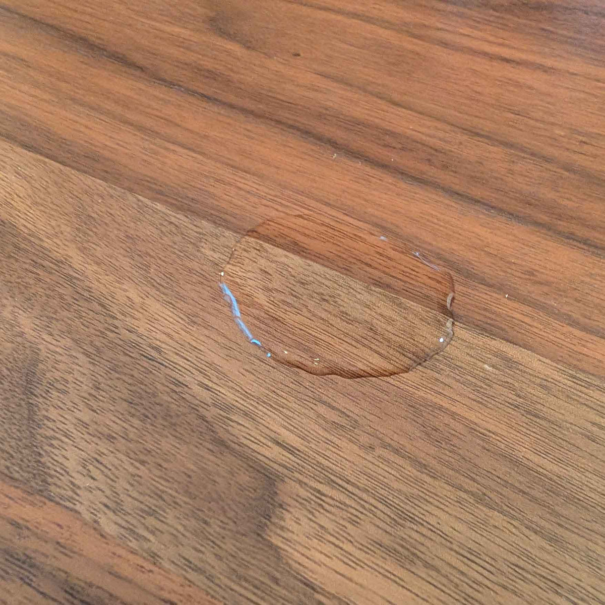 Water droplet resting on a sealed wood surface demonstrating the durable protective finish over rich grain