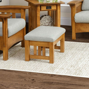 Small mission ottoman with light gray cushion and slatted oak legs on a patterned rug beside a matching chair