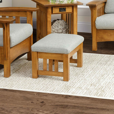 Small mission ottoman with light gray cushion and slatted oak legs on a patterned rug beside a matching chair