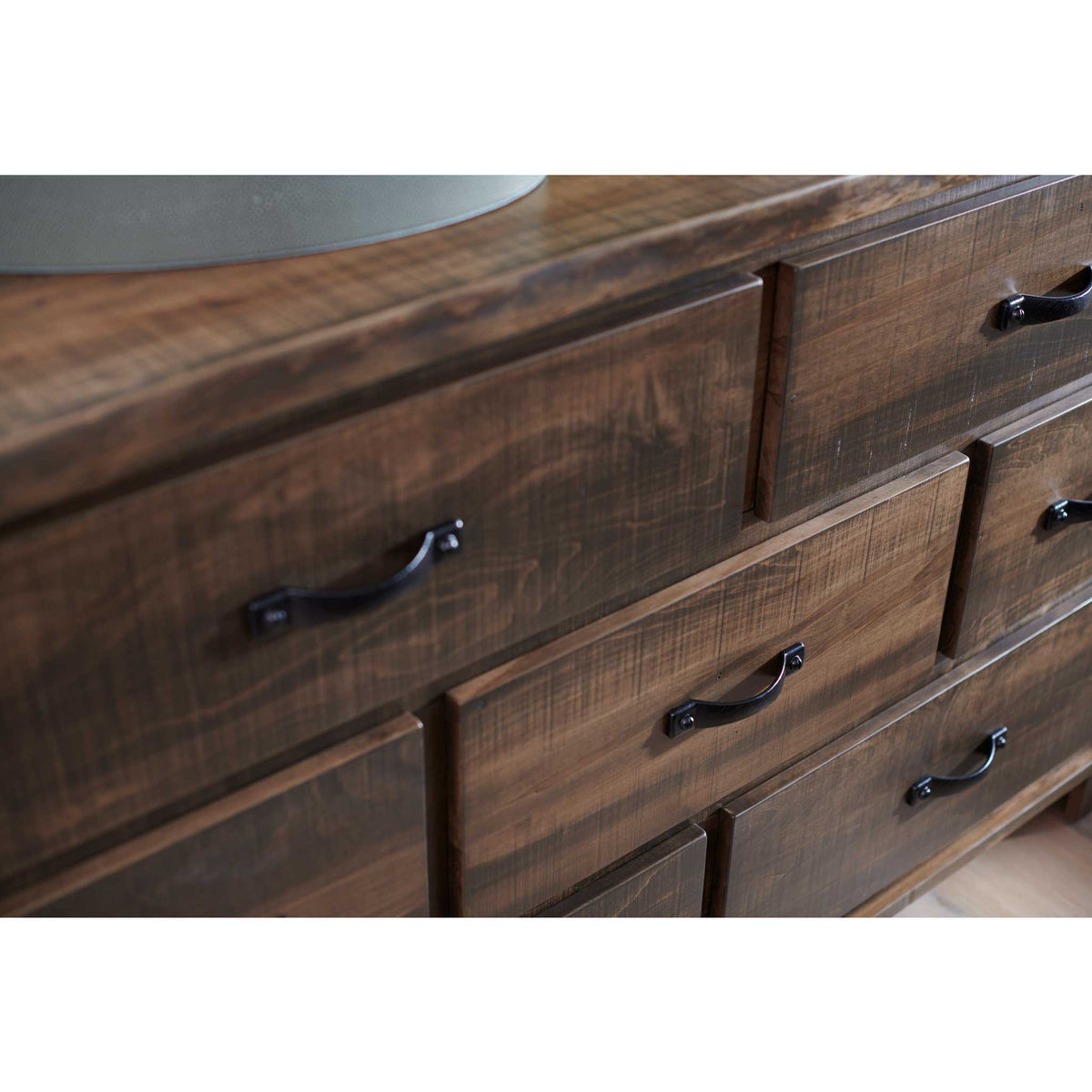 Close-up of the rustic dresser's saw-textured drawer fronts with curved black bin pulls beneath a gray tray