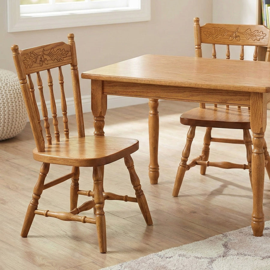 Two oak children's chairs with acorn carved backs pulled up to a matching kid-height oak play table