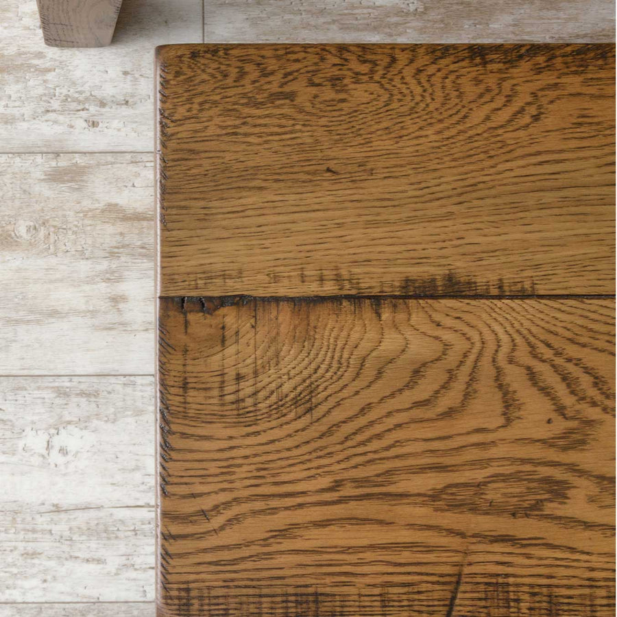 Close-up of the rough-sawn reclaimed-style oak tabletop corner showing heavy cathedral grain and distressed saw marks
