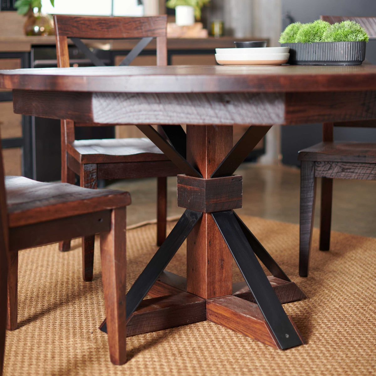 Pedestal base detail of the round dining table showing the reclaimed post, black metal legs and chair seats