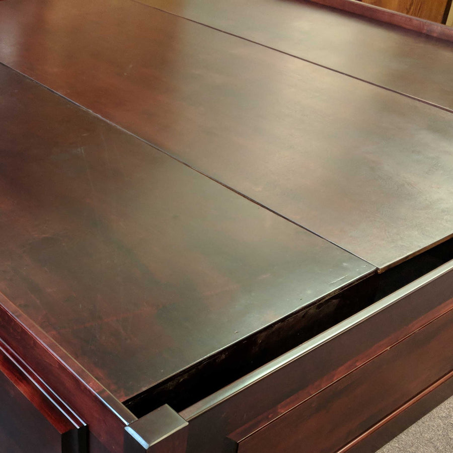 Close-up of a dark cherry bed platform top showing the flush panel seam and rail edge of the storage deck