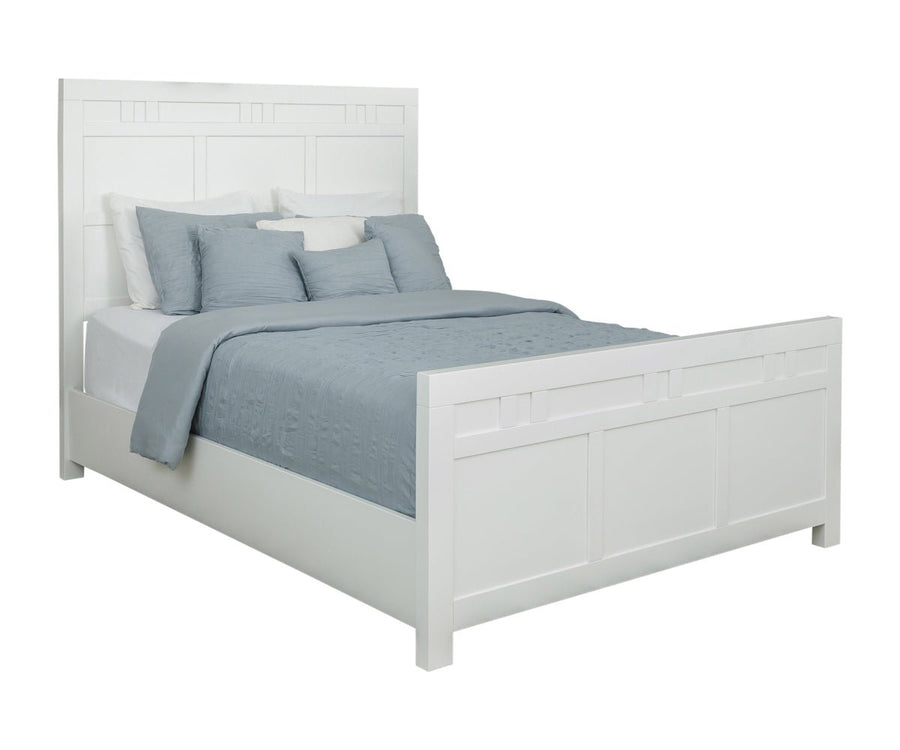 Angled view of a white painted queen panel bed with block-inlay headboard, matching paneled footboard and blue-gray quilt