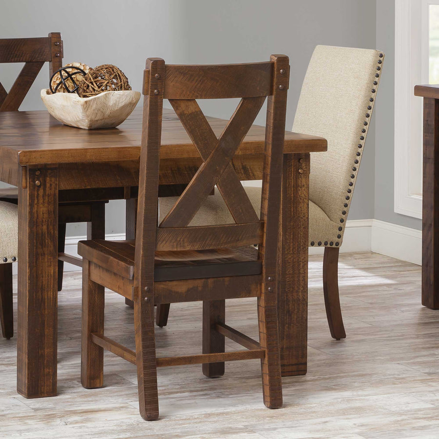 Rustic X back dining chair in distressed brown maple with plank seat and bolt accents at a rough-sawn table
