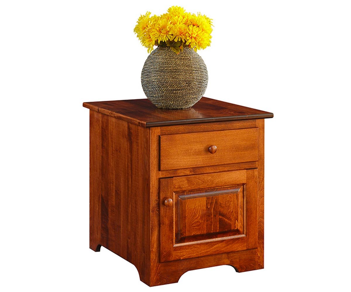 Cherry end table with one drawer, a raised panel door and a curved apron, topped with a woven vase of yellow flowers