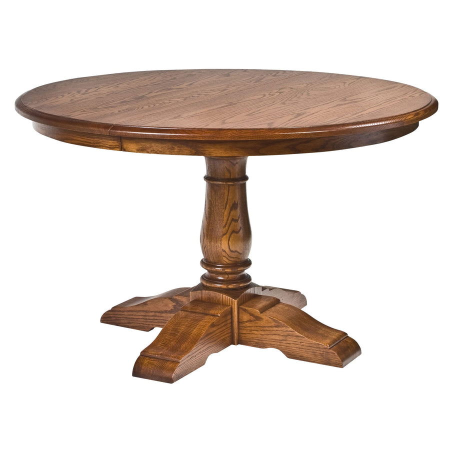 Round oak pedestal dining table with a turned column base and four scalloped feet on a white background