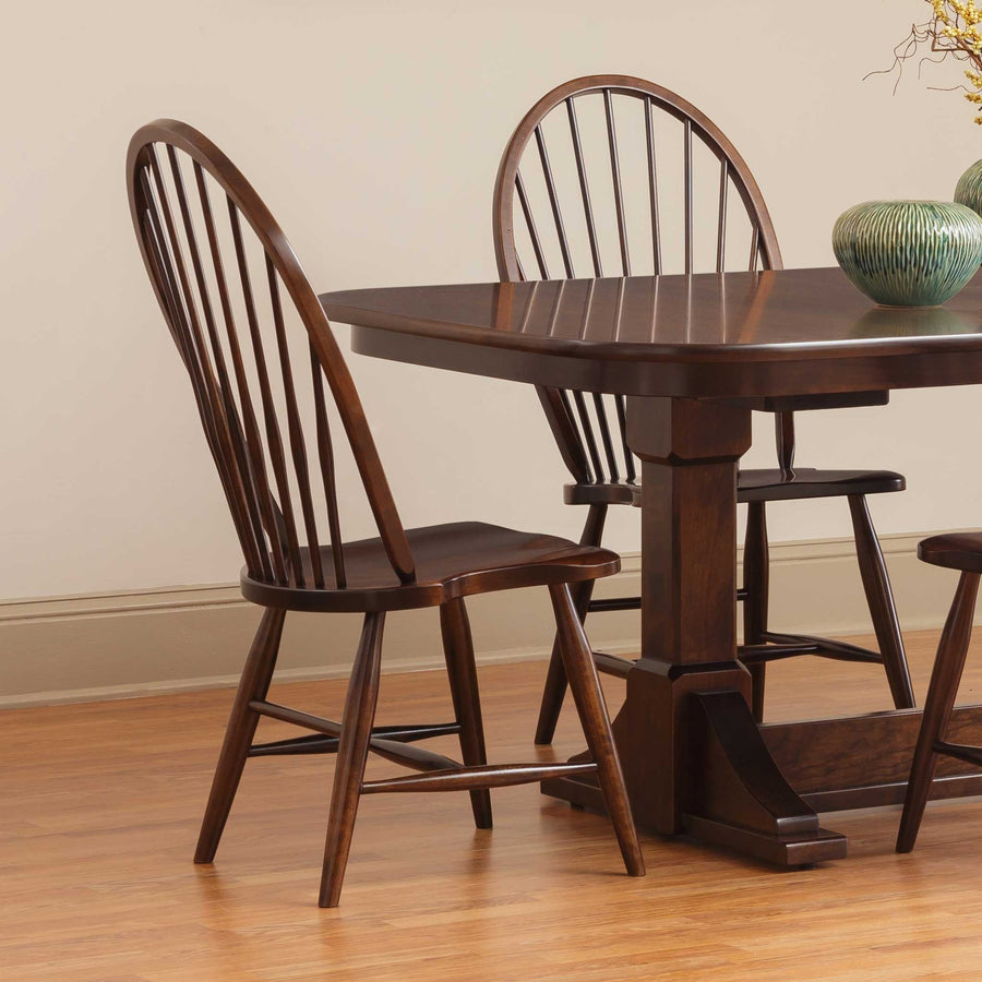 Bow back Windsor side chairs in a dark espresso finish beside a matching pedestal dining table on hardwood flooring