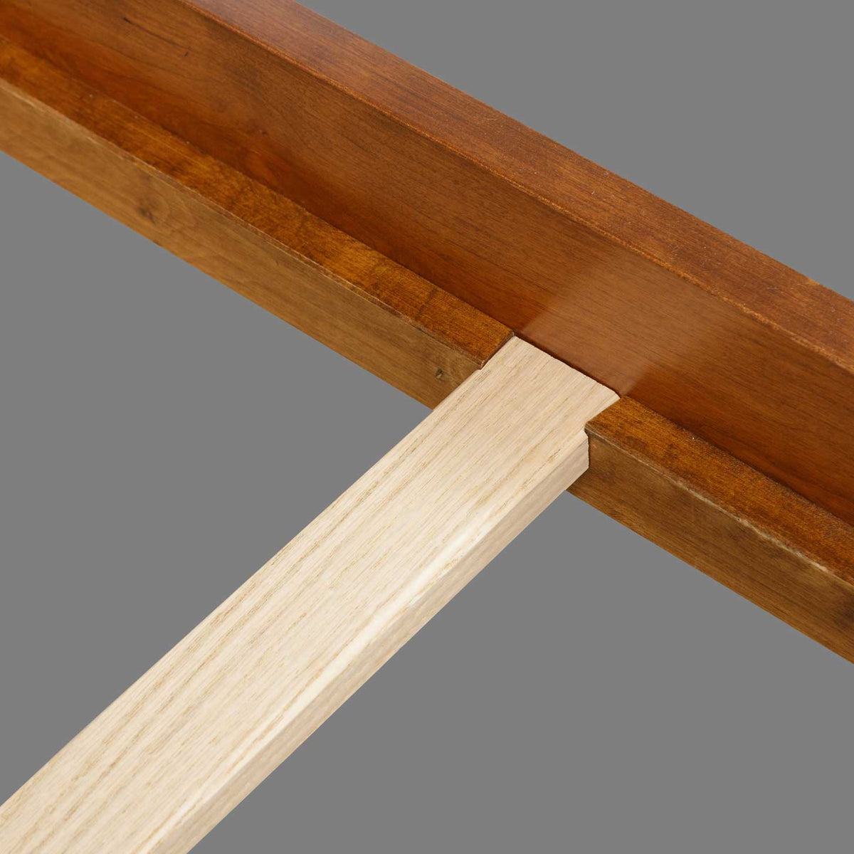 Notched cherry bed rail holding a natural maple slat, a close look at the bed's support joinery