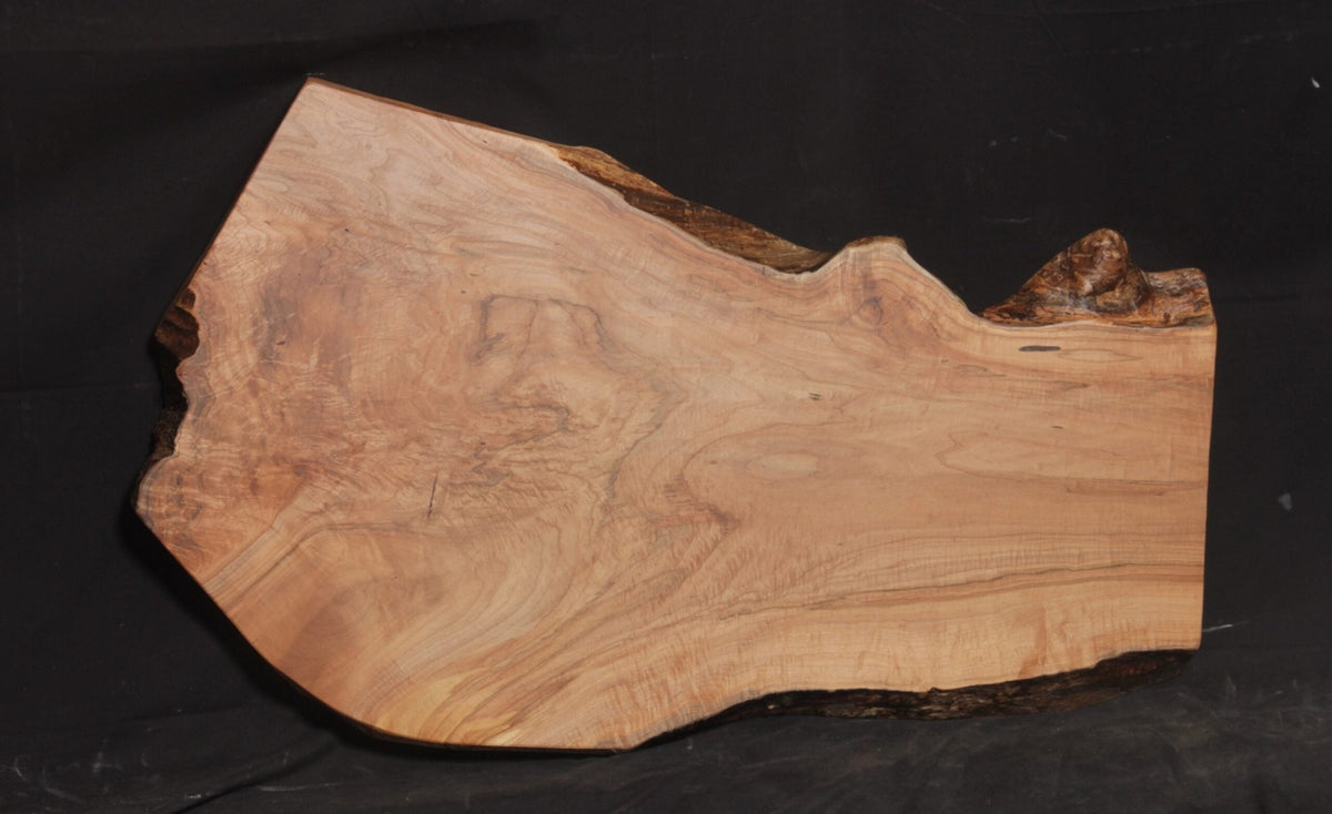 Maple live edge coffee table slab with flowing grain, natural bark edges and a wide curved profile on black