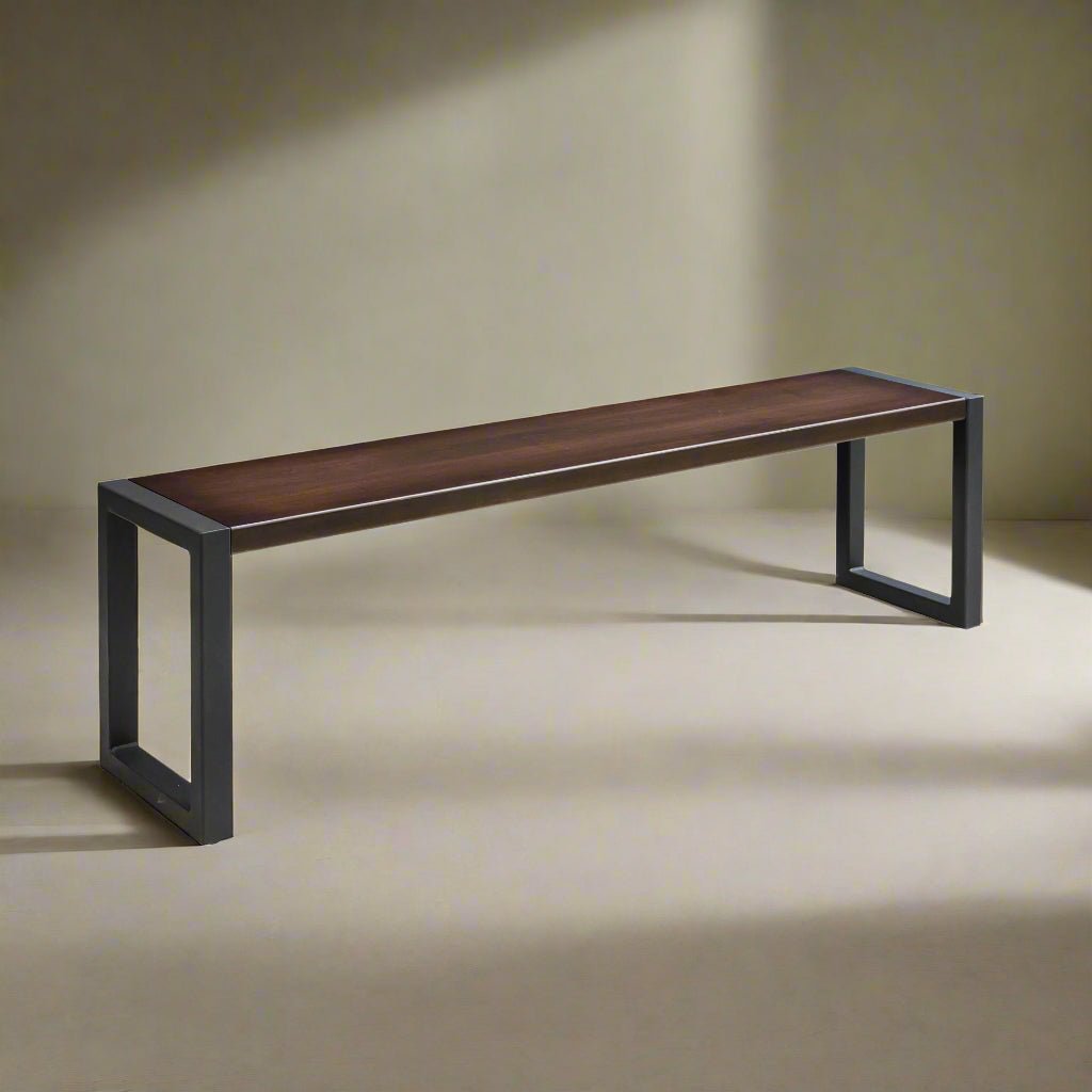 Solid wood dining bench with a dark walnut seat plank set in blackened steel loop legs, lit by a spotlight