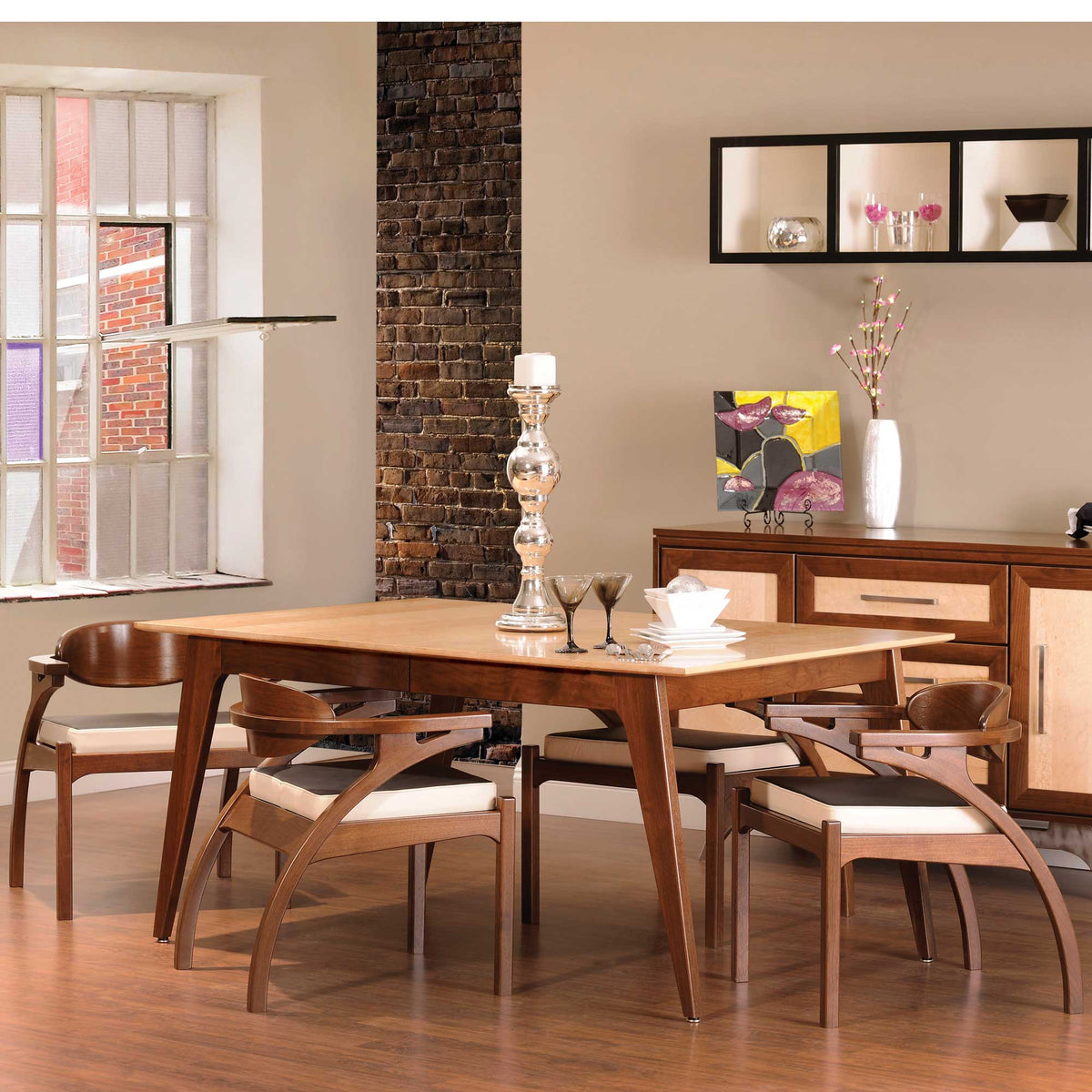 Mid century modern dining table with a maple top and walnut angled legs, set with curved arm chairs in a loft