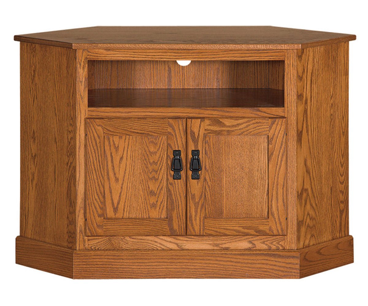 Oak Mission corner TV stand with an open component shelf, two panel doors with black hardware and a canted base