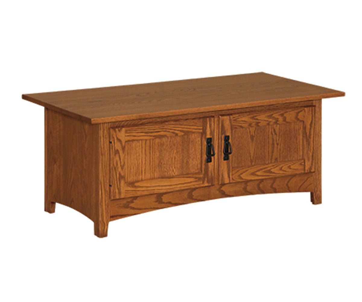Mission oak coffee table with two paneled doors, black hardware and a curved apron on a white background