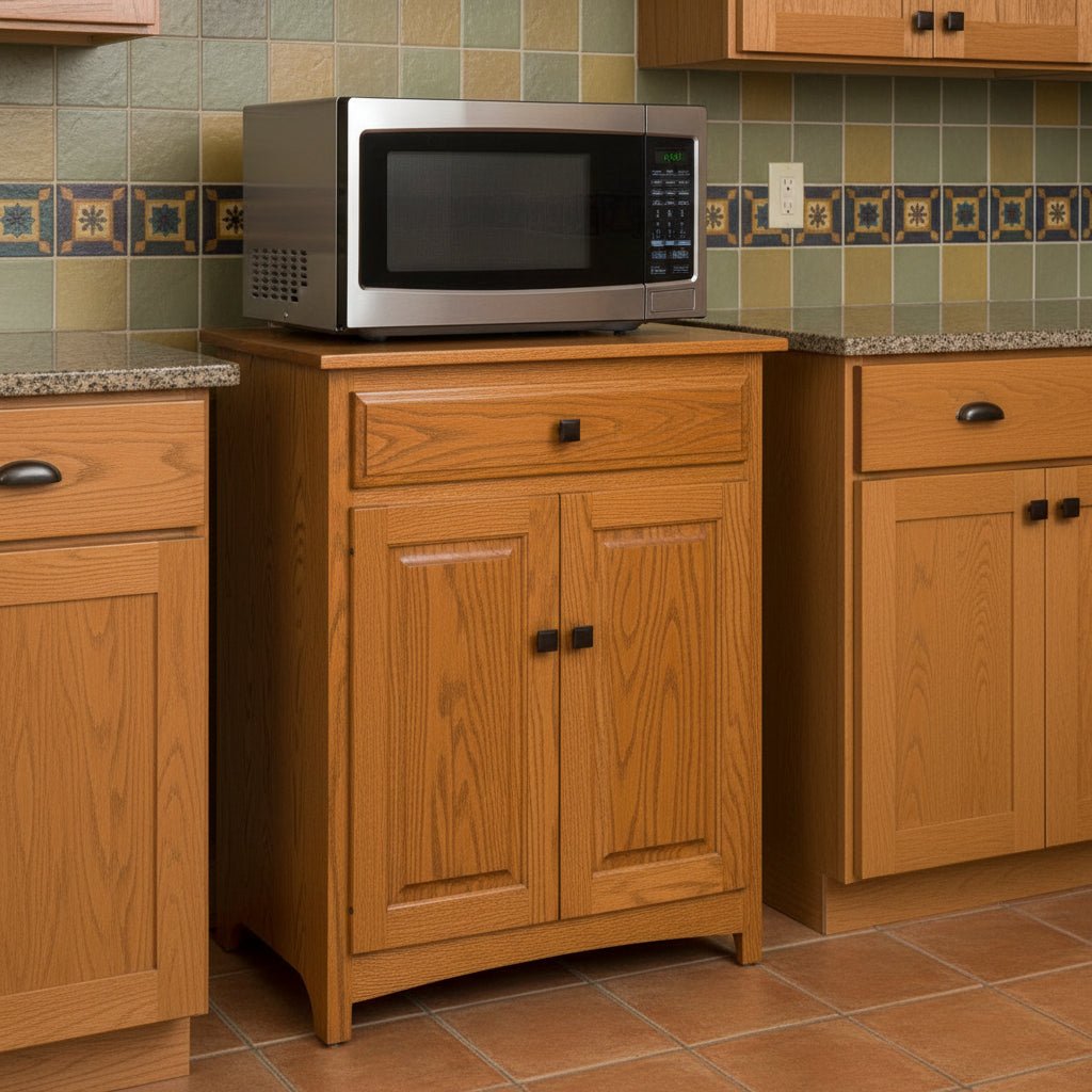 Oak microwave stand with a drawer and two paneled doors, holding a stainless microwave in a tiled oak kitchen