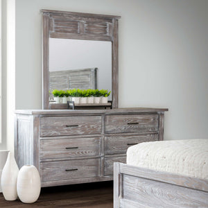 Weathered gray six drawer dresser with matching louvered mirror styled in a bedroom with white vases