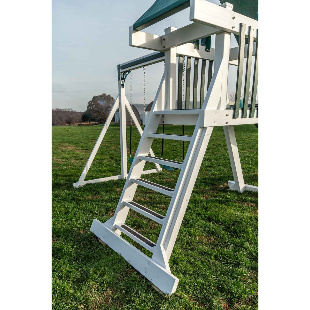 Close-up of the white vinyl playset ladder with wide treads and a bolted frame standing on green lawn