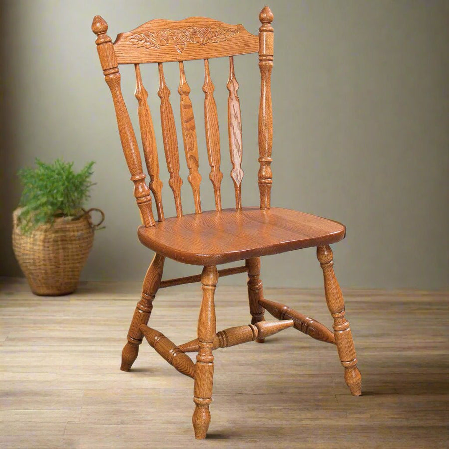 Oak spindle dining chair with a carved wheat crest, urn shaped spindles and a sculpted saddle seat