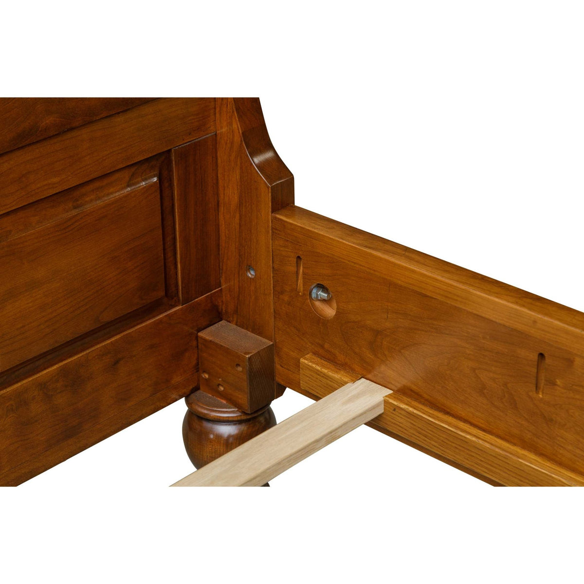 Corner detail of a cherry sleigh bed headboard, turned bun foot and side rail with a bolt fastener and slat