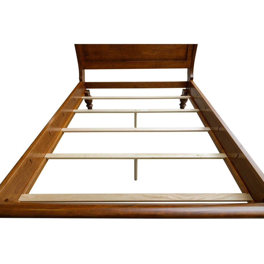 Cherry sleigh bed frame shown without mattress, revealing pale maple support slats and turned bun feet
