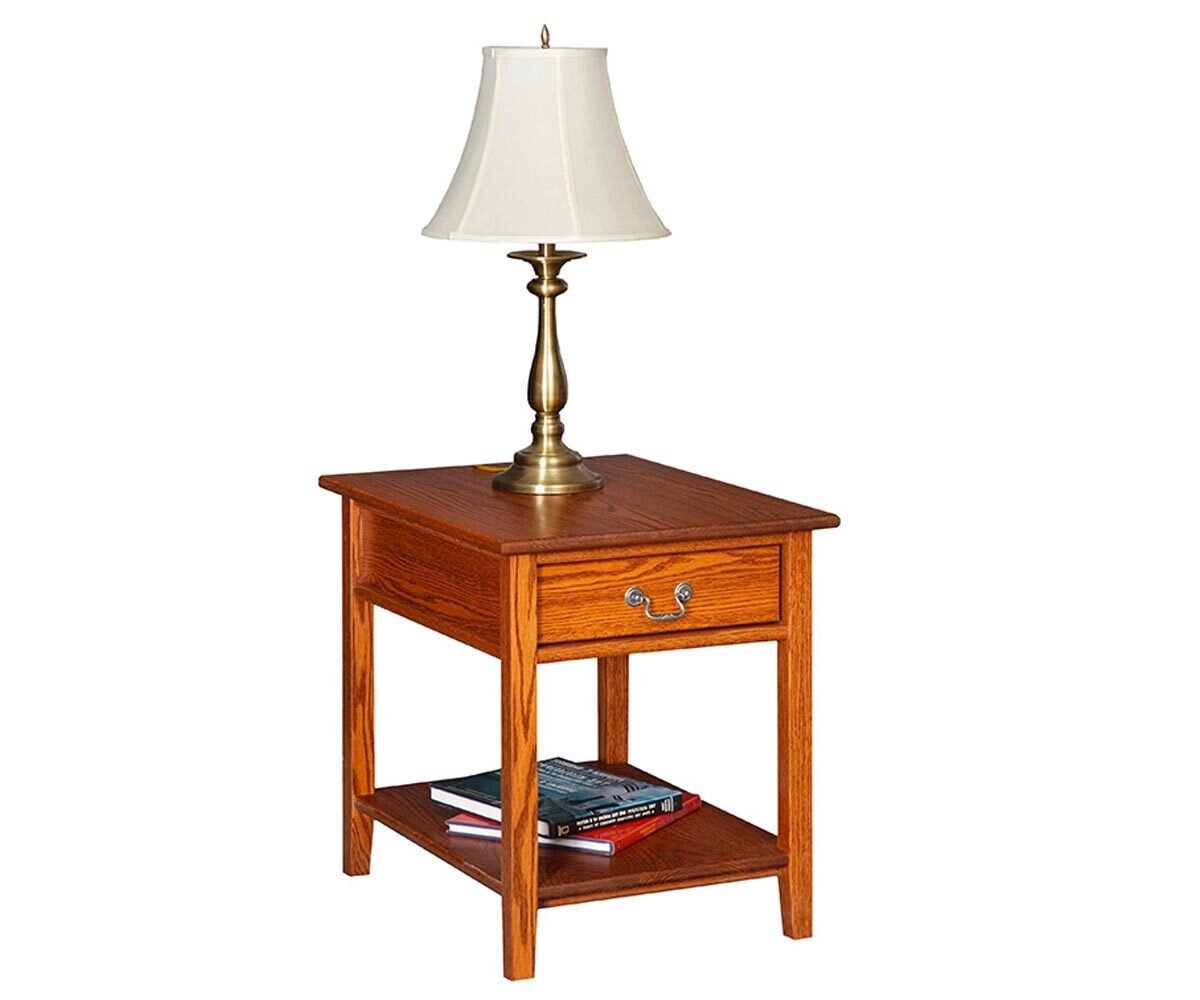 Oak Shaker end table with a drawer, brass bail pull and a lower shelf holding books, topped with a brass lamp