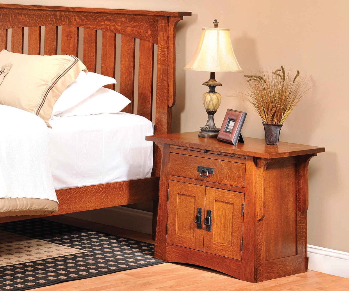 Oak door nightstand with lamp and framed photo beside a mission slat bed on a patterned rug