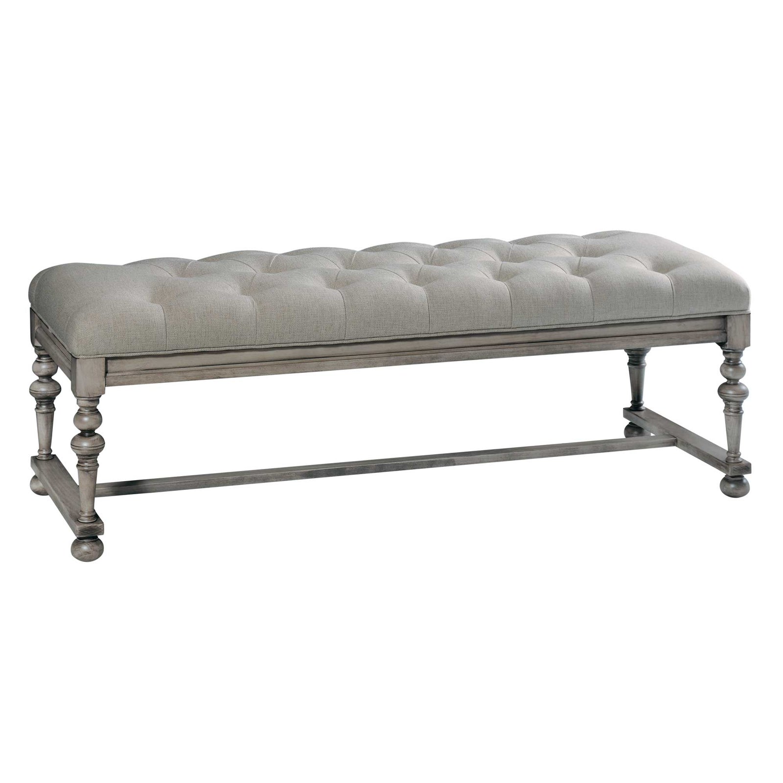 Gray tufted linen bedroom bench with turned legs and stretcher base placed at the foot of an upholstered bed