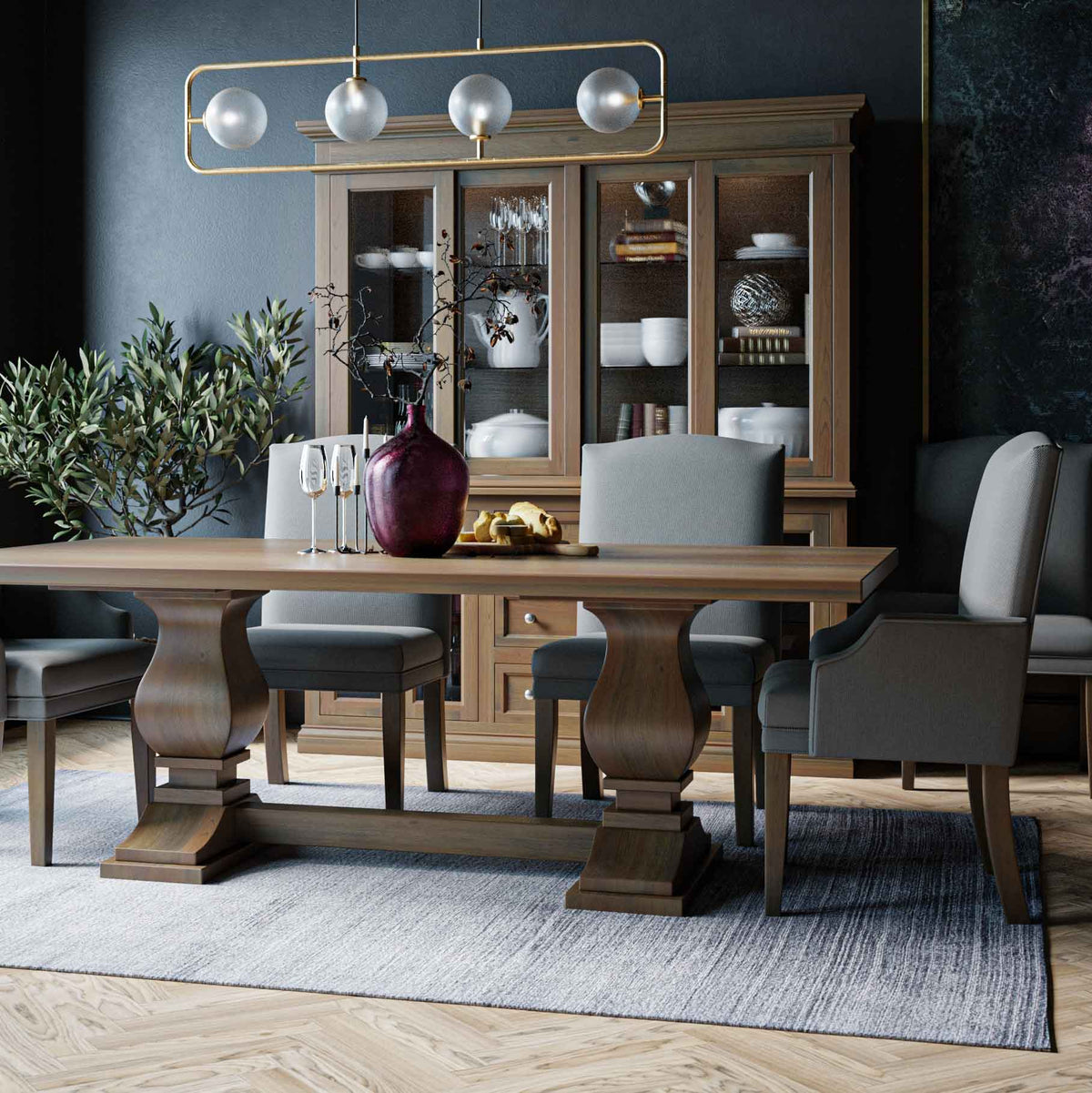 Light oak lighted china cabinet with glass doors behind a pedestal dining table and upholstered chairs