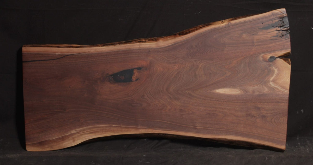 Rectangular walnut live edge slab 61 inches long and 21 to 33 inches wide with rich swirling grain on black