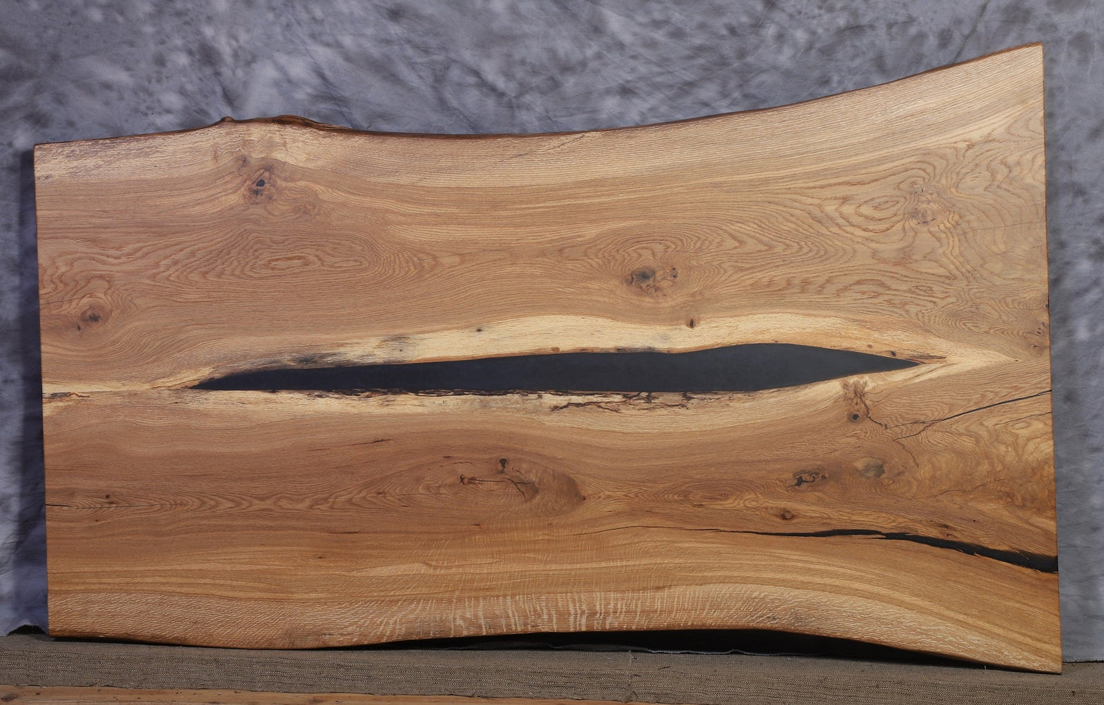 White oak live edge slab 75 inches long and 37 to 46 inches wide with a dark epoxy filled center crack