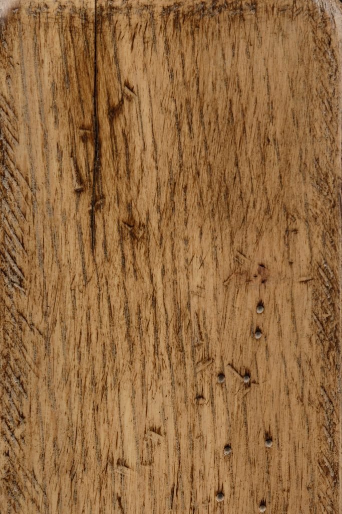 Seashell antiqued finish on rustic quartersawn white oak, a light tan board with flecked grain and dark distress marks