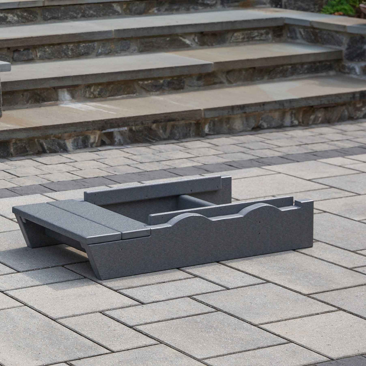 Pair of dark gray poly lumber glider risers on a paver patio, showing the contoured base platform