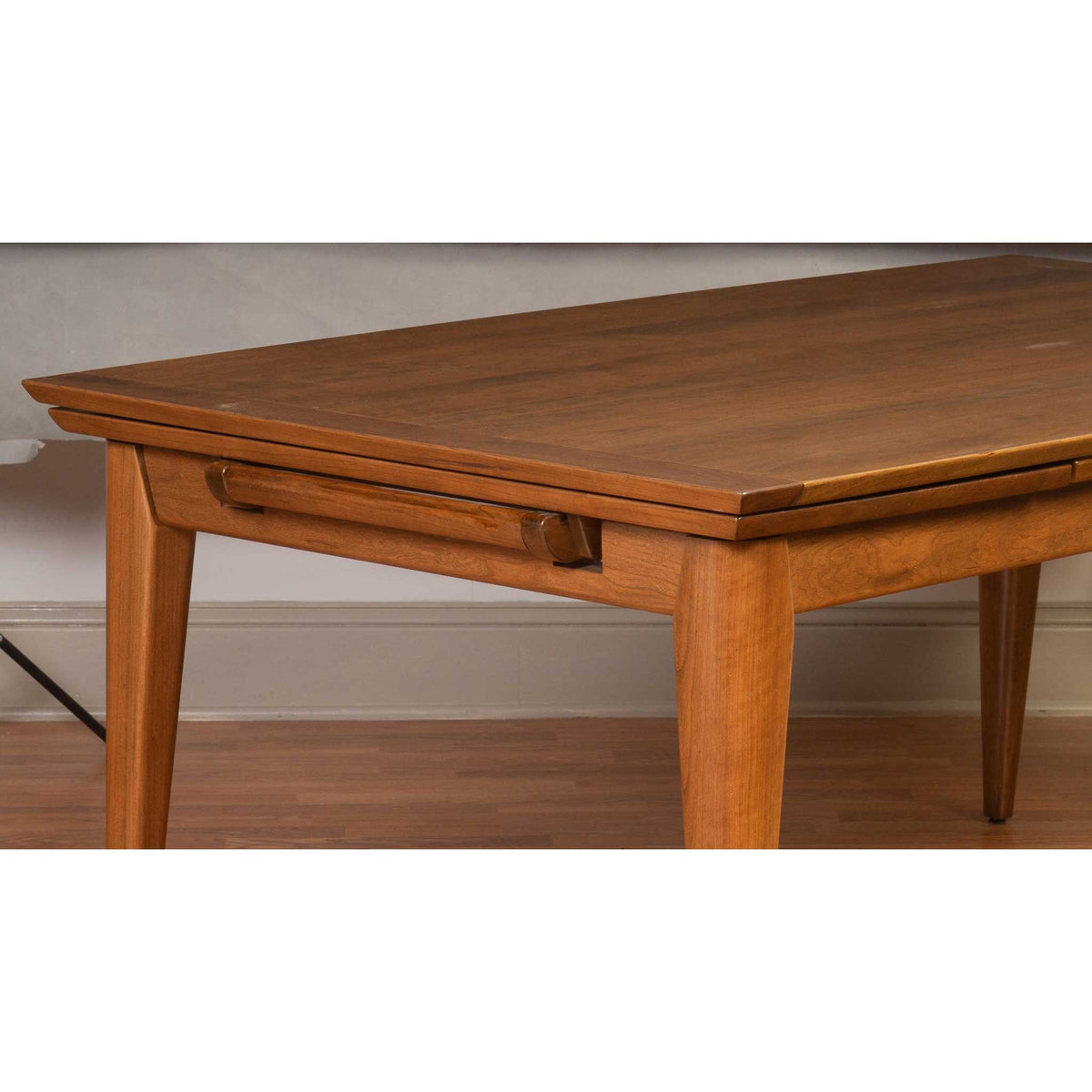 Detail of the draw leaf table showing the mitered top edge, sliding leaf pull and tapered mid-century leg