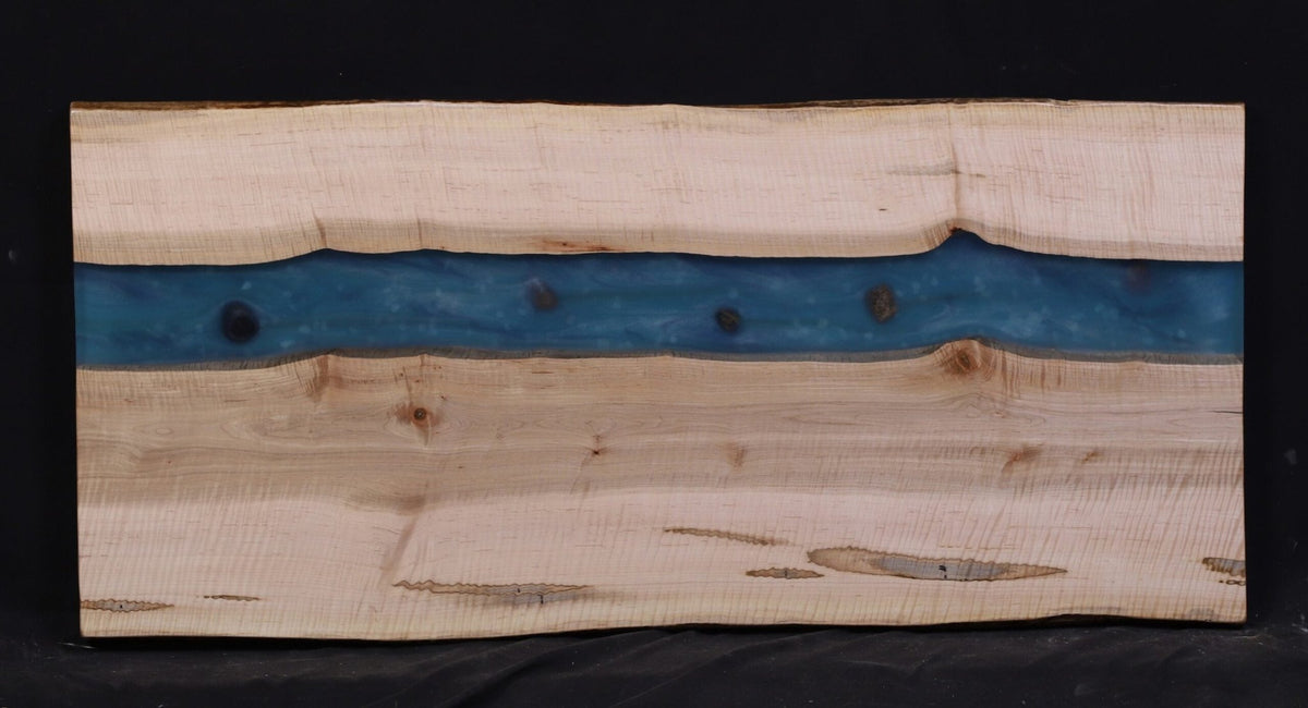 Curly maple slab with pale silvery grain and a teal blue epoxy river winding between the two live edges