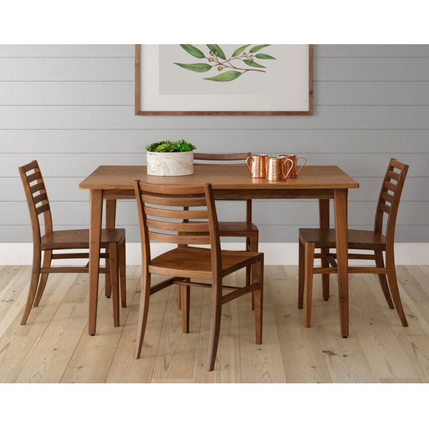 Walnut mid-century modern dining table with four ladder back chairs, copper mugs and a planter in a light room