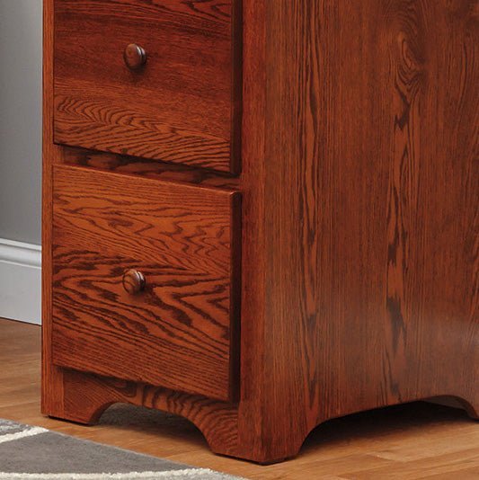 Close-up of the lower drawers and scalloped base of a solid oak file cabinet in a medium cherry stain