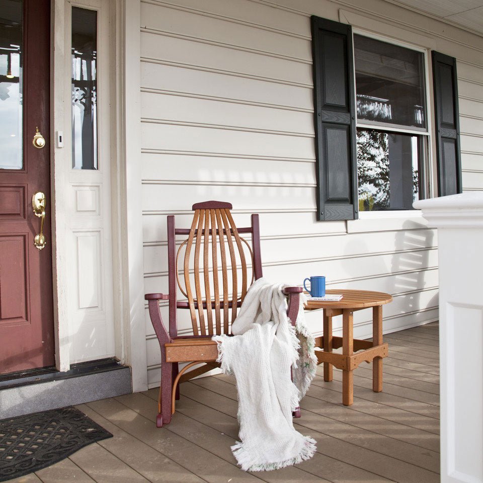 Cedar and cherry poly rocking chair with a white throw on a farmhouse porch beside a round side table