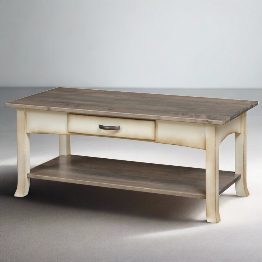 Coastal coffee table with driftwood gray plank top, distressed cream legs, one drawer and open shelf on grey